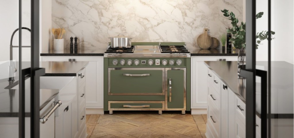 A modern kitchen featuring a green gas range with brass accents, set against a marble backsplash and light cabinetry.